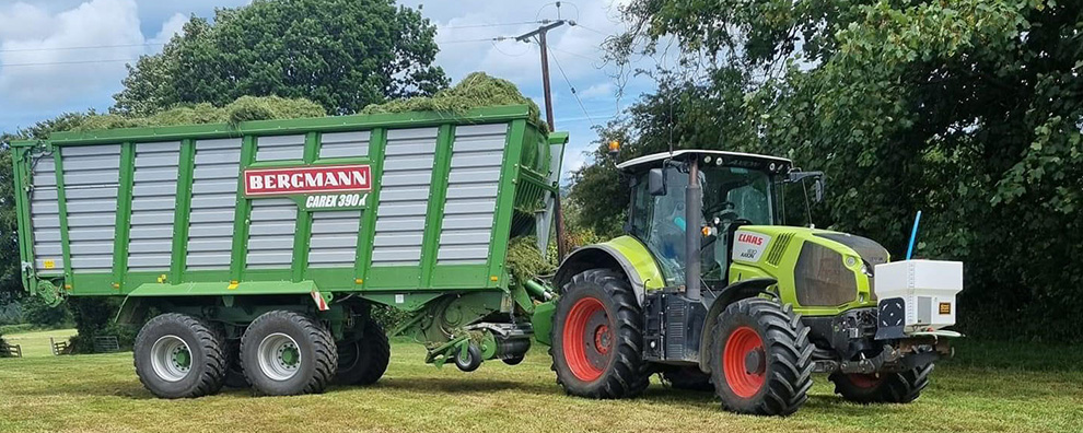 Silage additive applicator mounted on the front link arms of a tractor